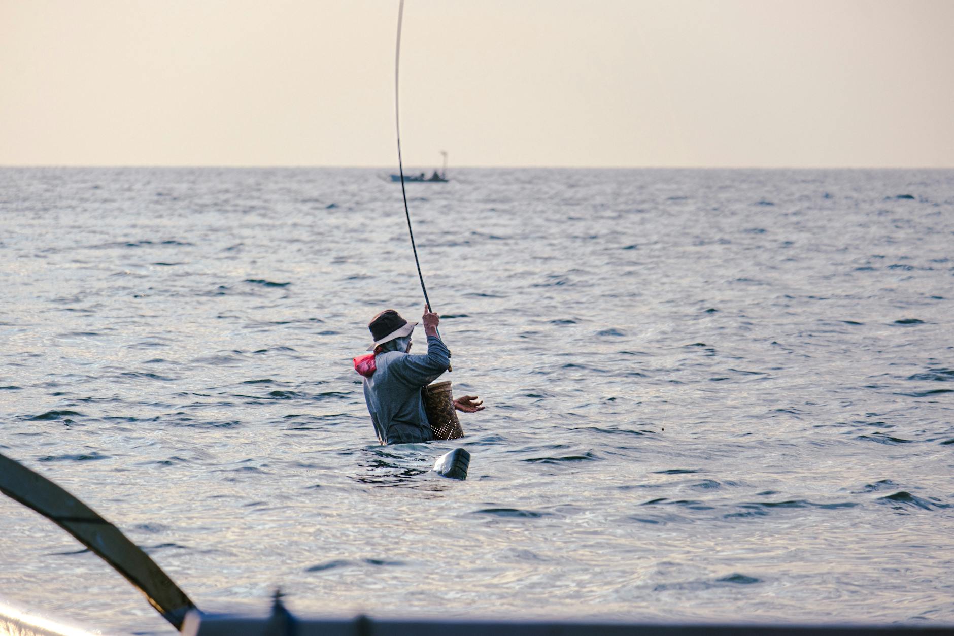 Angler standing in shallow saltwater casting with a fishing rod on a calm day