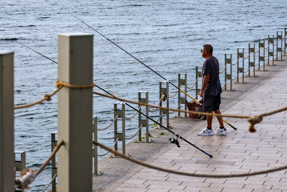 Angler on shore fighting a fish with rod held high and bent in a smooth arc