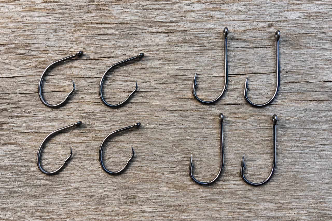 Circle hooks and traditional J-hooks compared side by side on a wooden surface